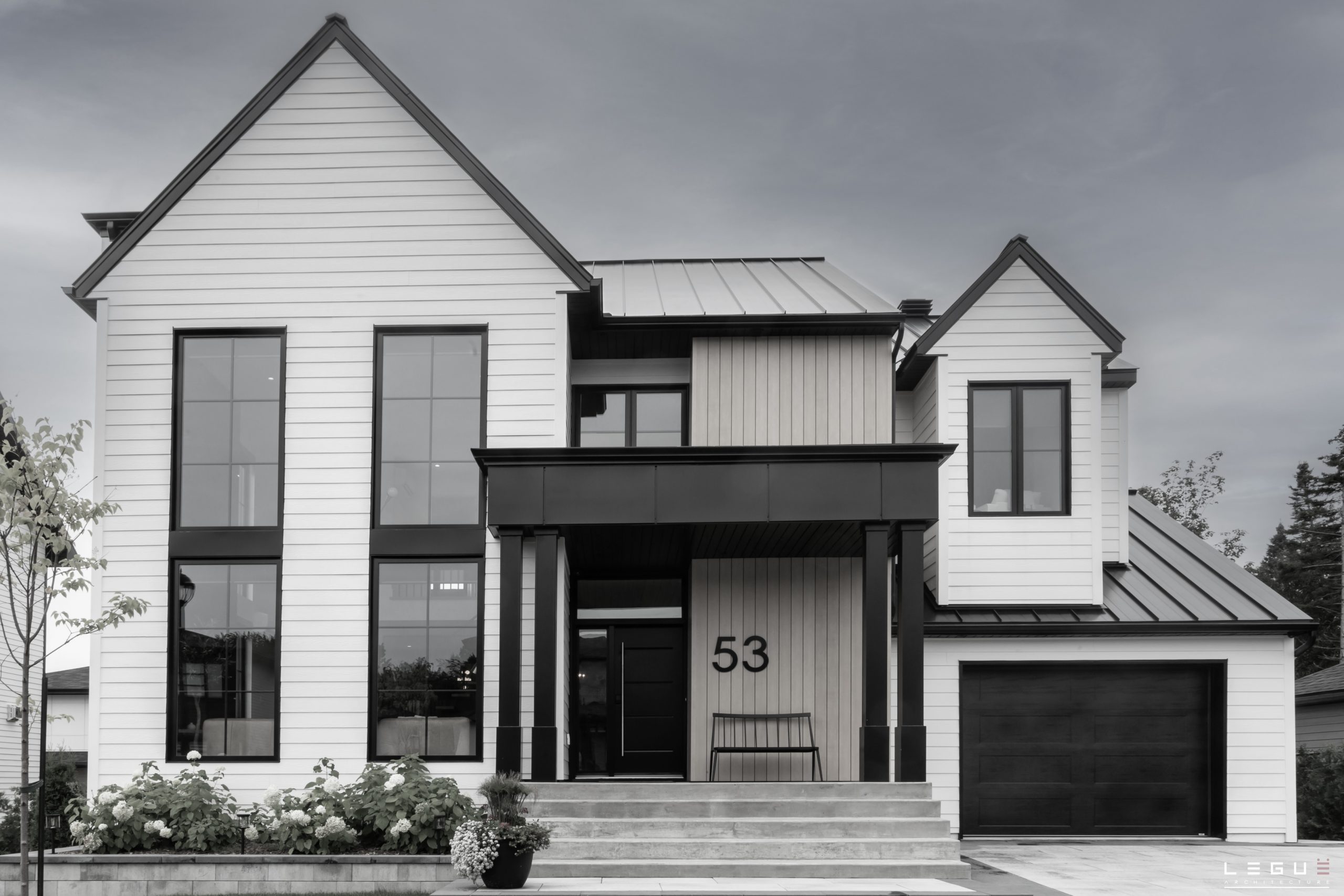Maison unifamiliale moderne au revêtement blanc et aux fenêtres noires