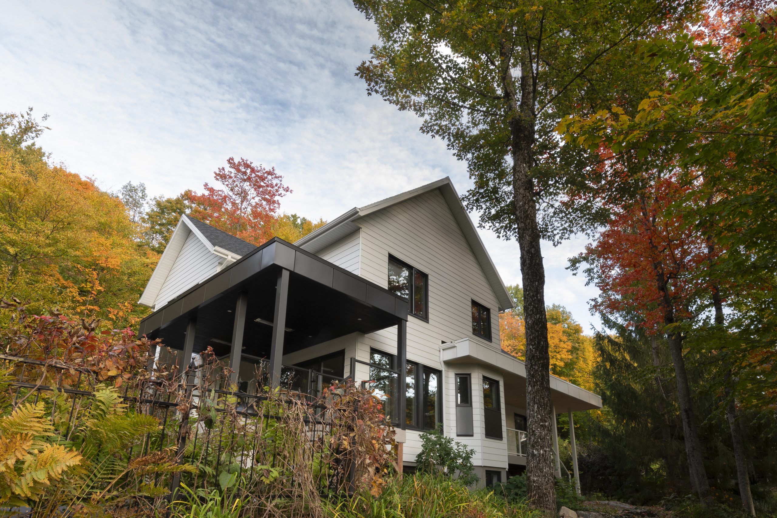 Maison moderne à deux étages dans un boisé aux couleurs d’automne